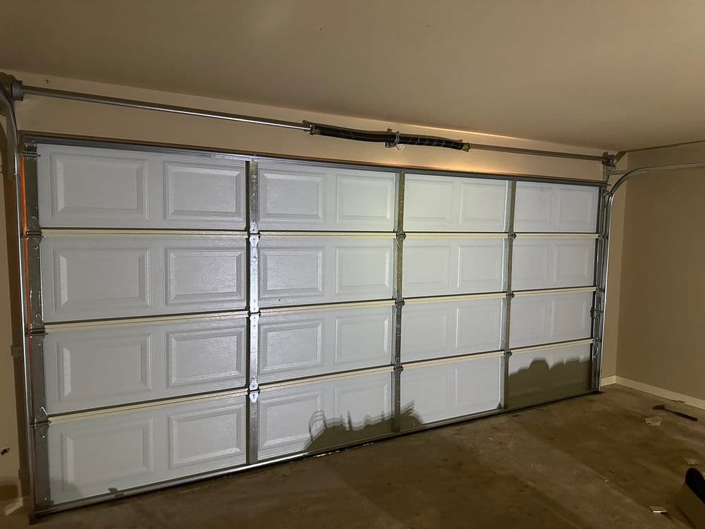 White garage door in a spacious, empty garage interior with concrete flooring.