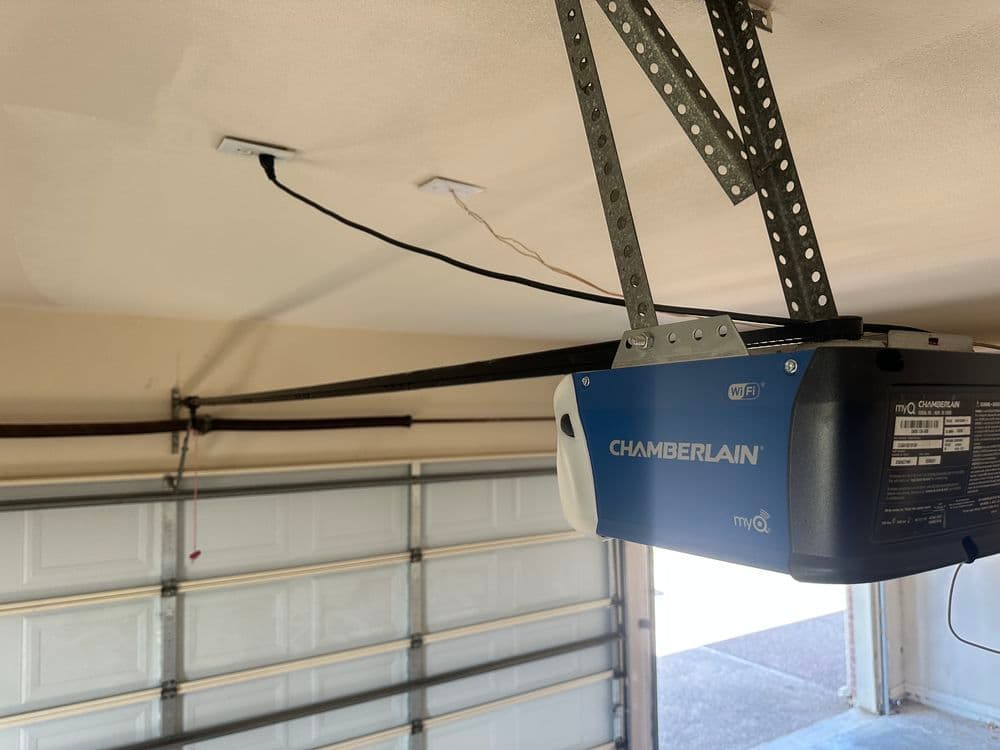 Wi-Fi enabled Chamberlain garage door opener with mounted sensors in residential garage.