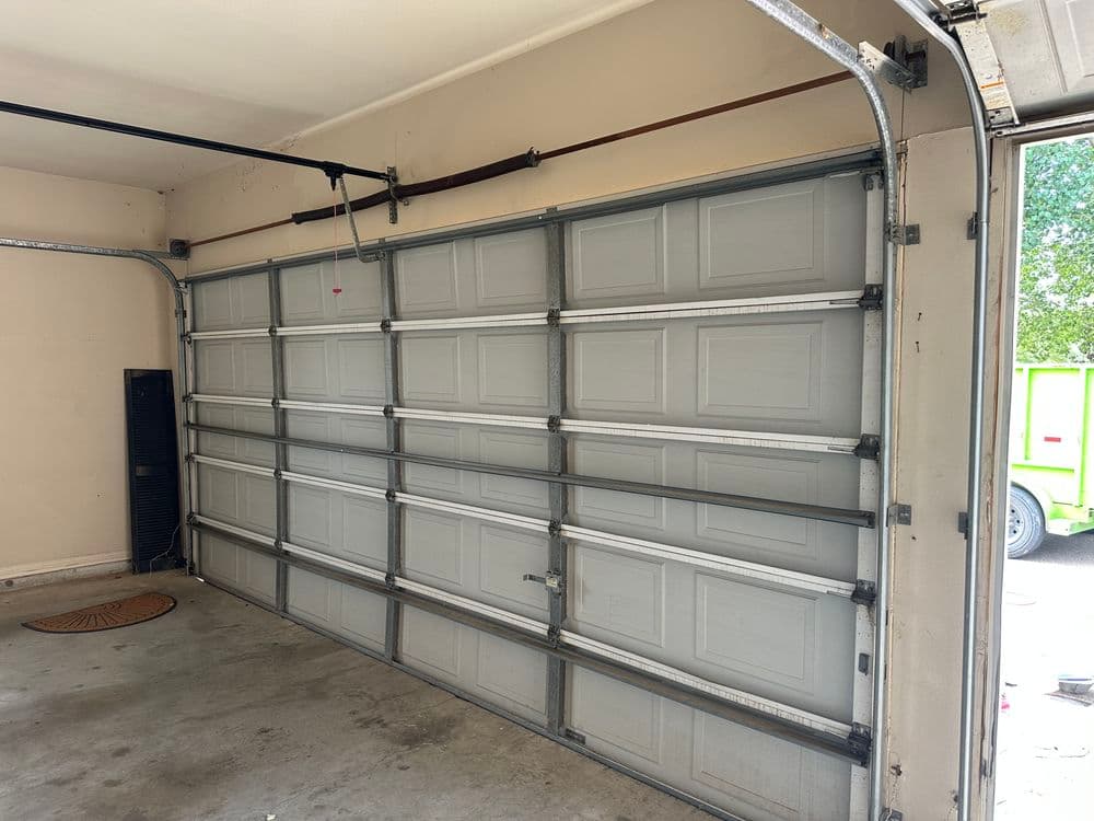 Interior view of a garage with a closed sectional garage door and concrete flooring.