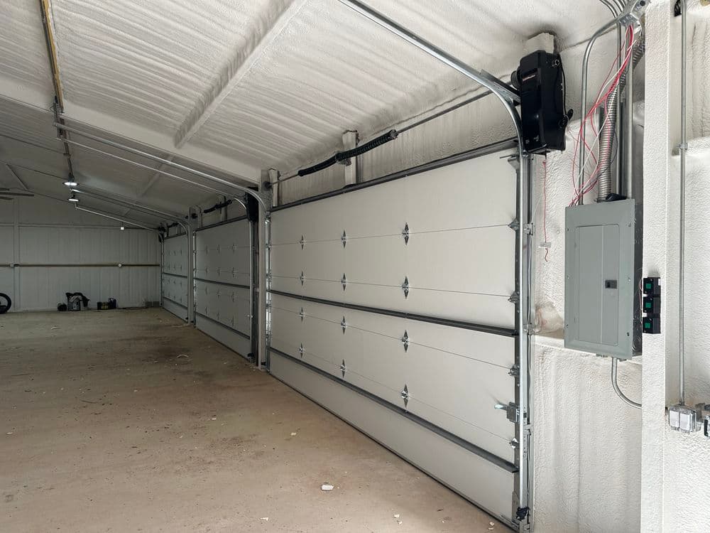 Interior of a spacious garage with closed garage doors and electrical panel on the wall.