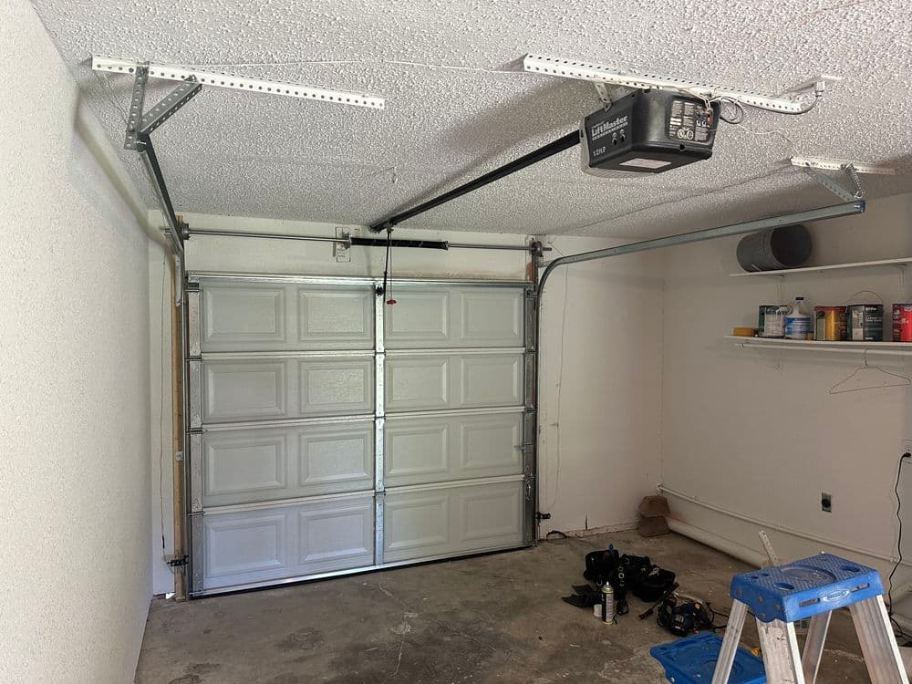 Interior view of a garage with a closed garage door and storage shelves on the side.