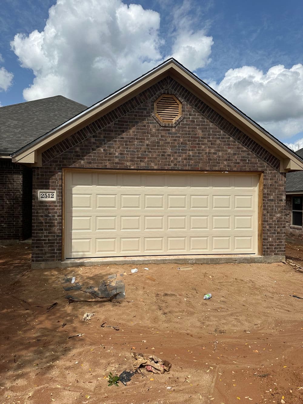 Newly built home garage with a cream door and brick exterior, located at 2512.