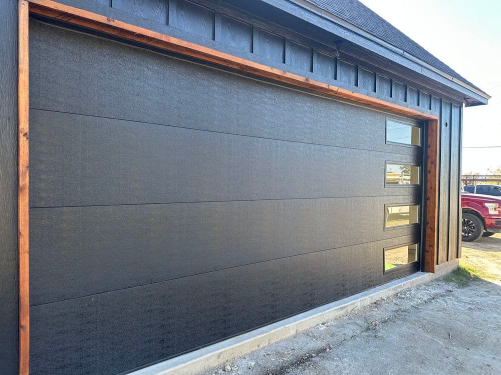 Modern black garage door with wood accents in a contemporary home design.