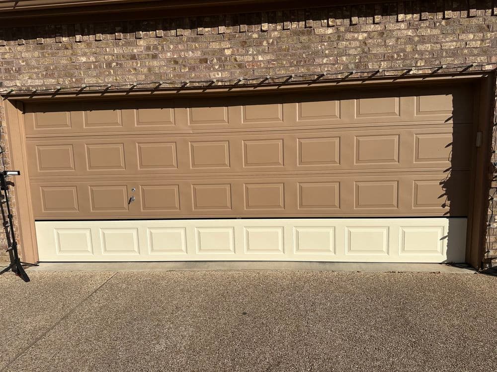 Two-tone garage door with a brown upper section and cream lower section against a brick wall.